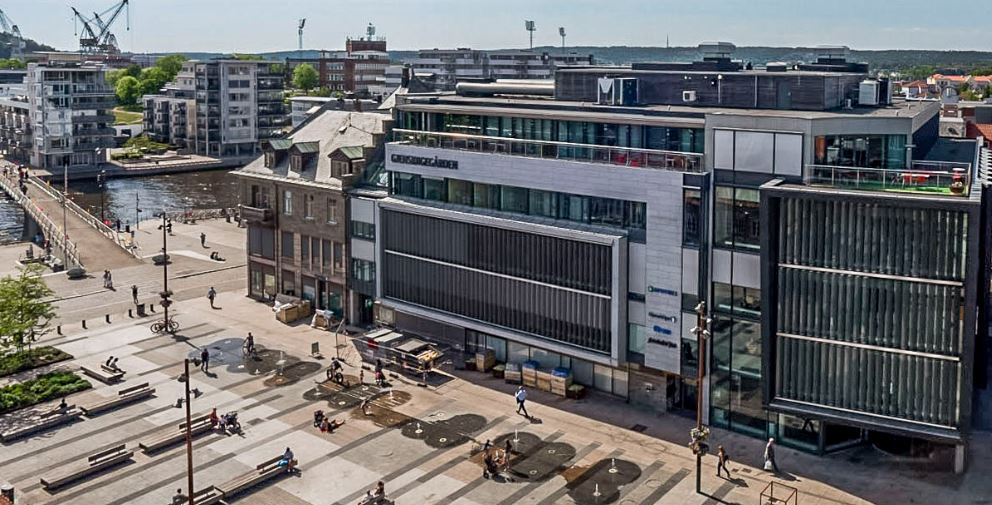 Bygning i et bymiljø med et torv foran. Foto.
