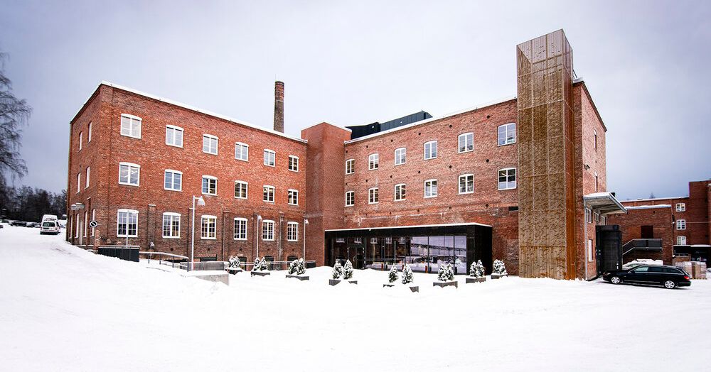 Tre etasjes kontorbygg i rød teglstein. Det er snø på bakken. Foto.