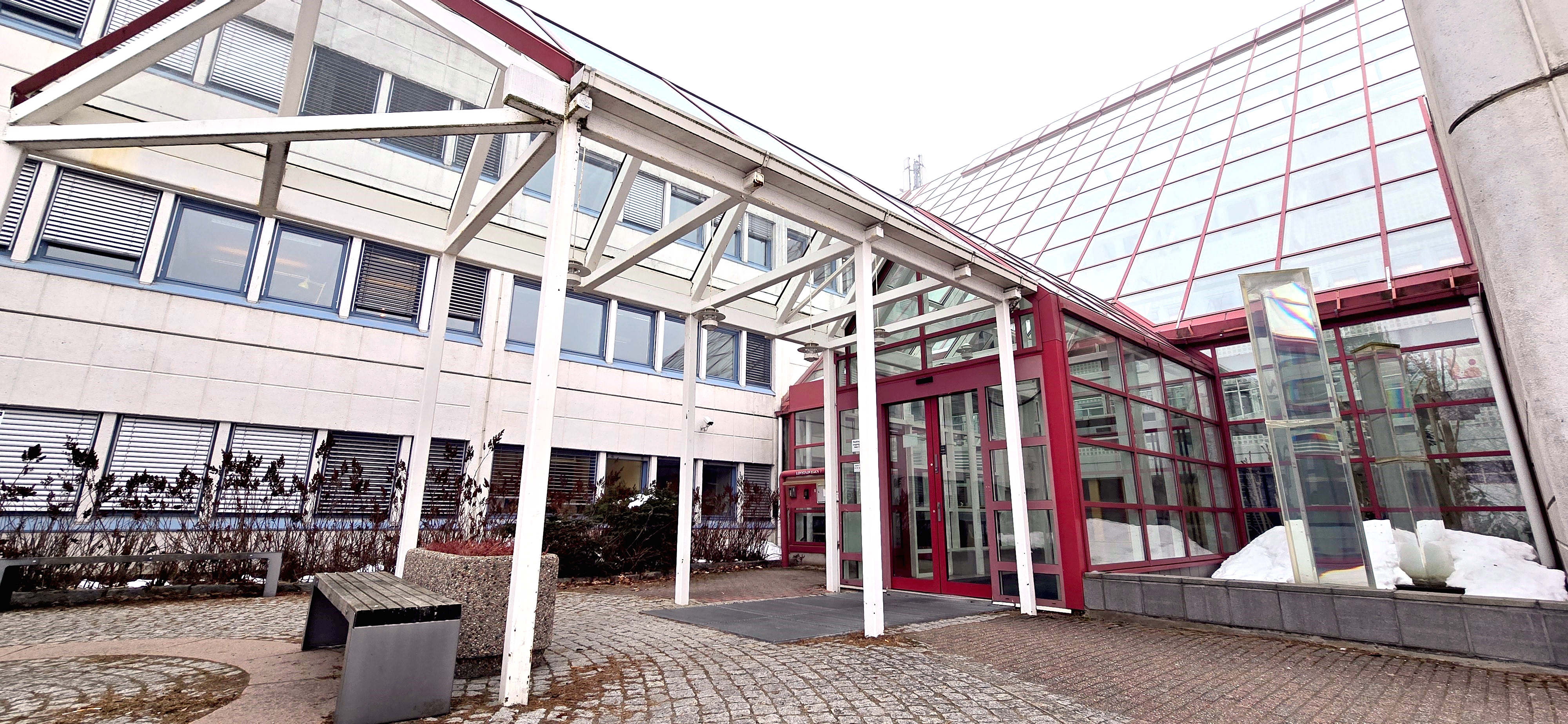 En hvit kontorbygning med søyler og innglasset inngangsparti. Foto.