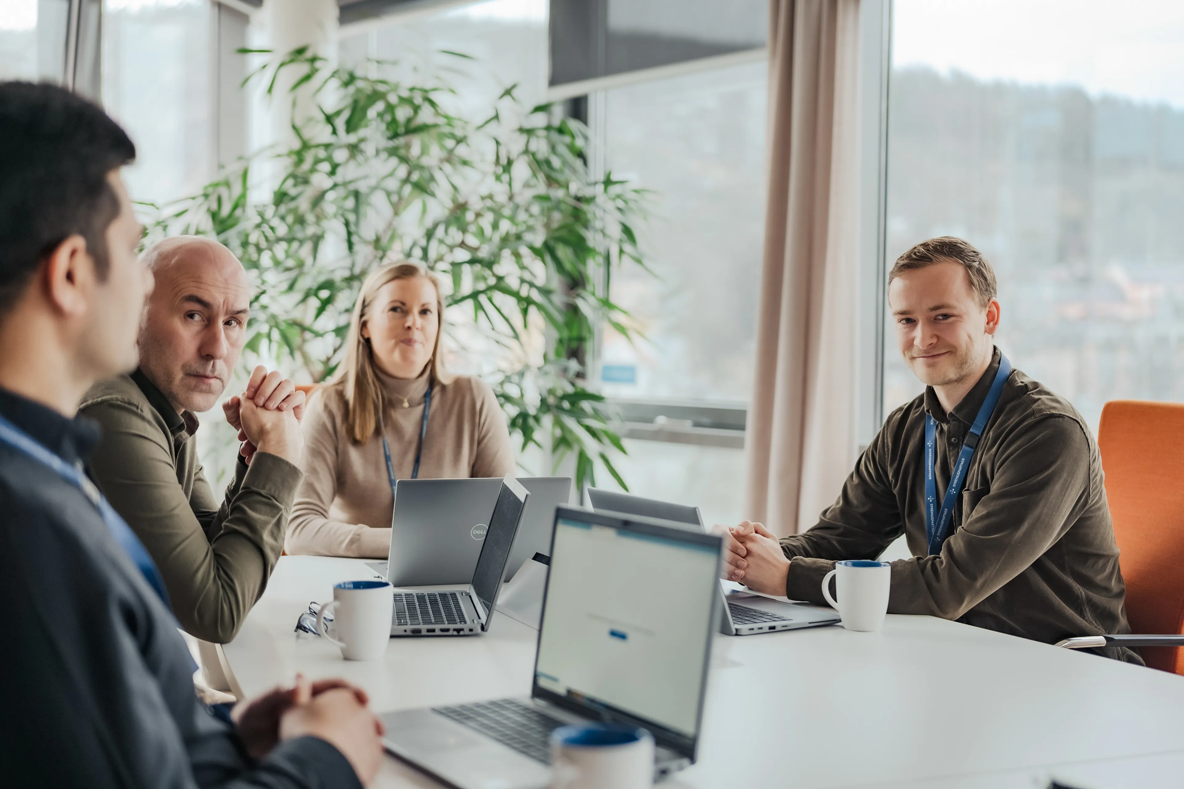 En gruppe mennesker som sitter rundt et bord med bærbare datamaskiner