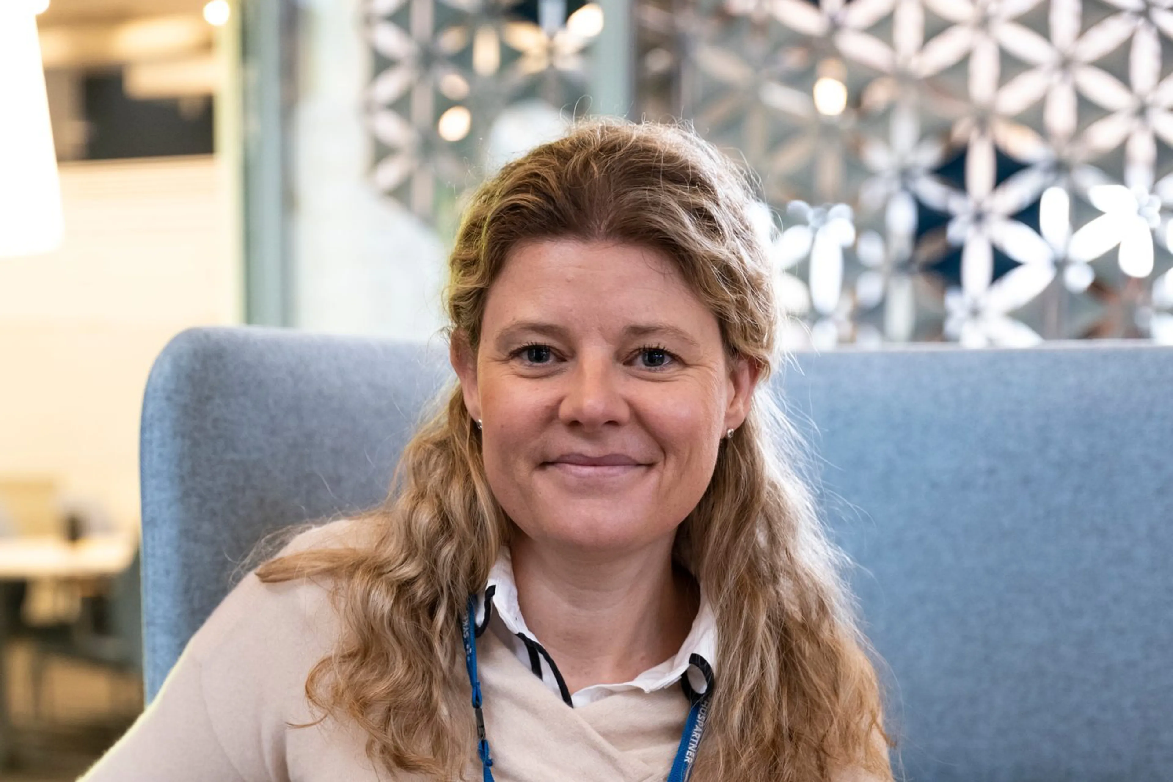 En kvinne med langt blondt hår, som sitter i en stol. Foto.