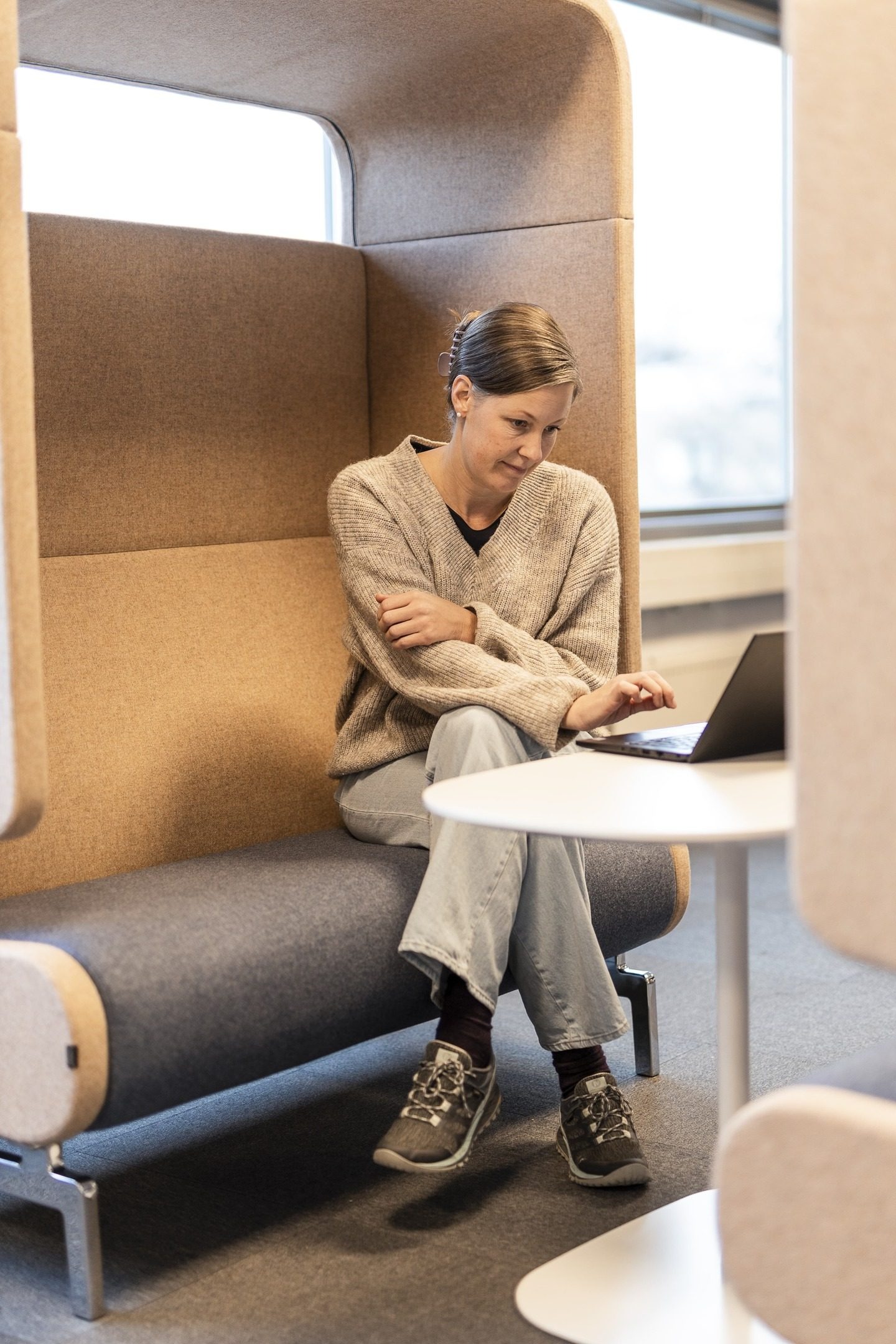 En kvinne som sitter på et kontor, ser på en PC-skjerm. Foto.