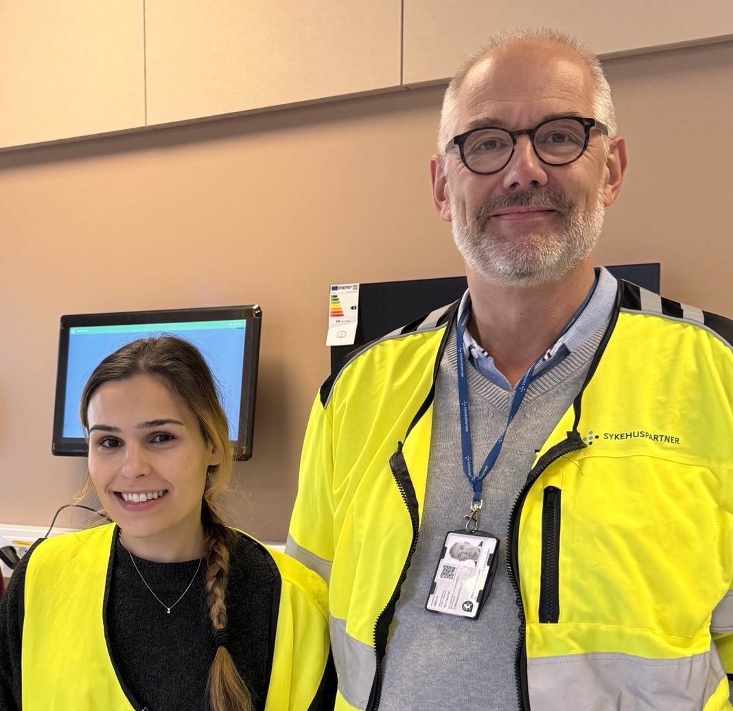 Smilende mann og kvinne i gule vester som poserer for et bilde