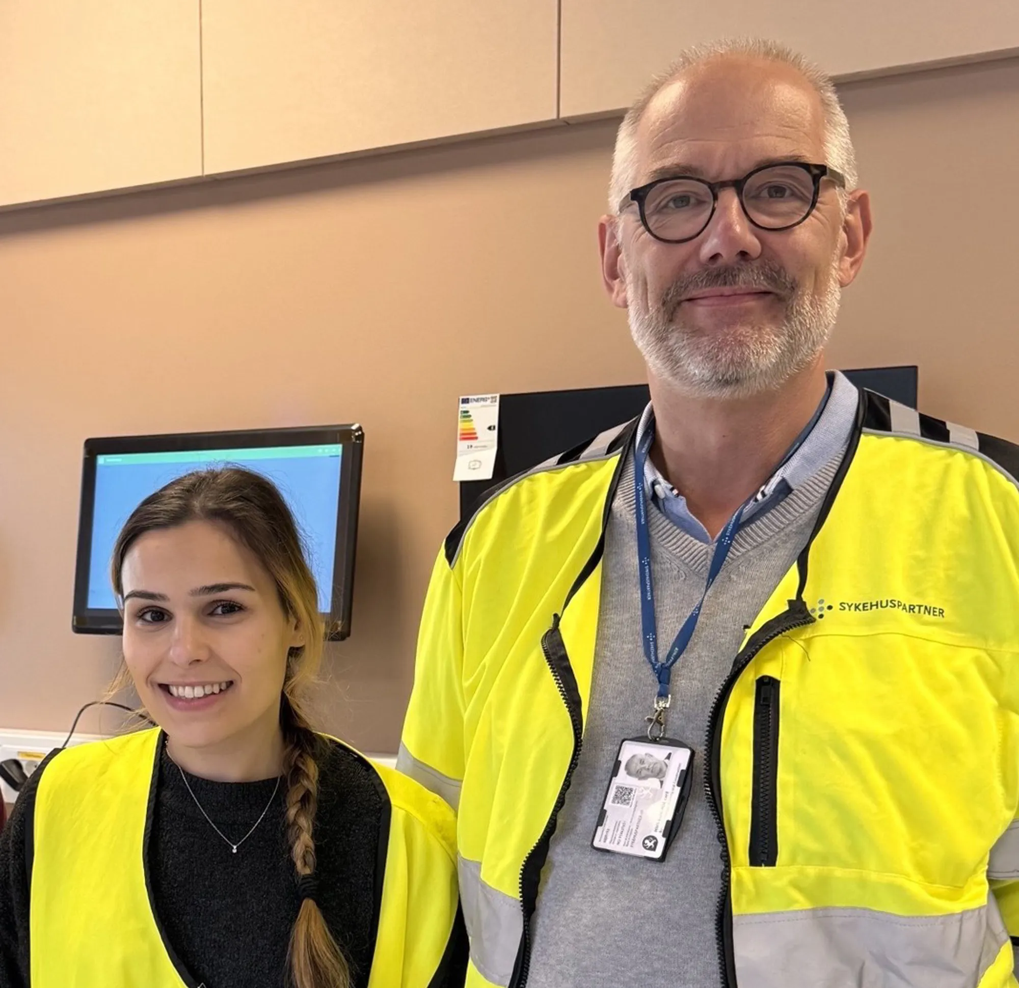 Smilende mann og kvinne i gule vester som poserer for et bilde