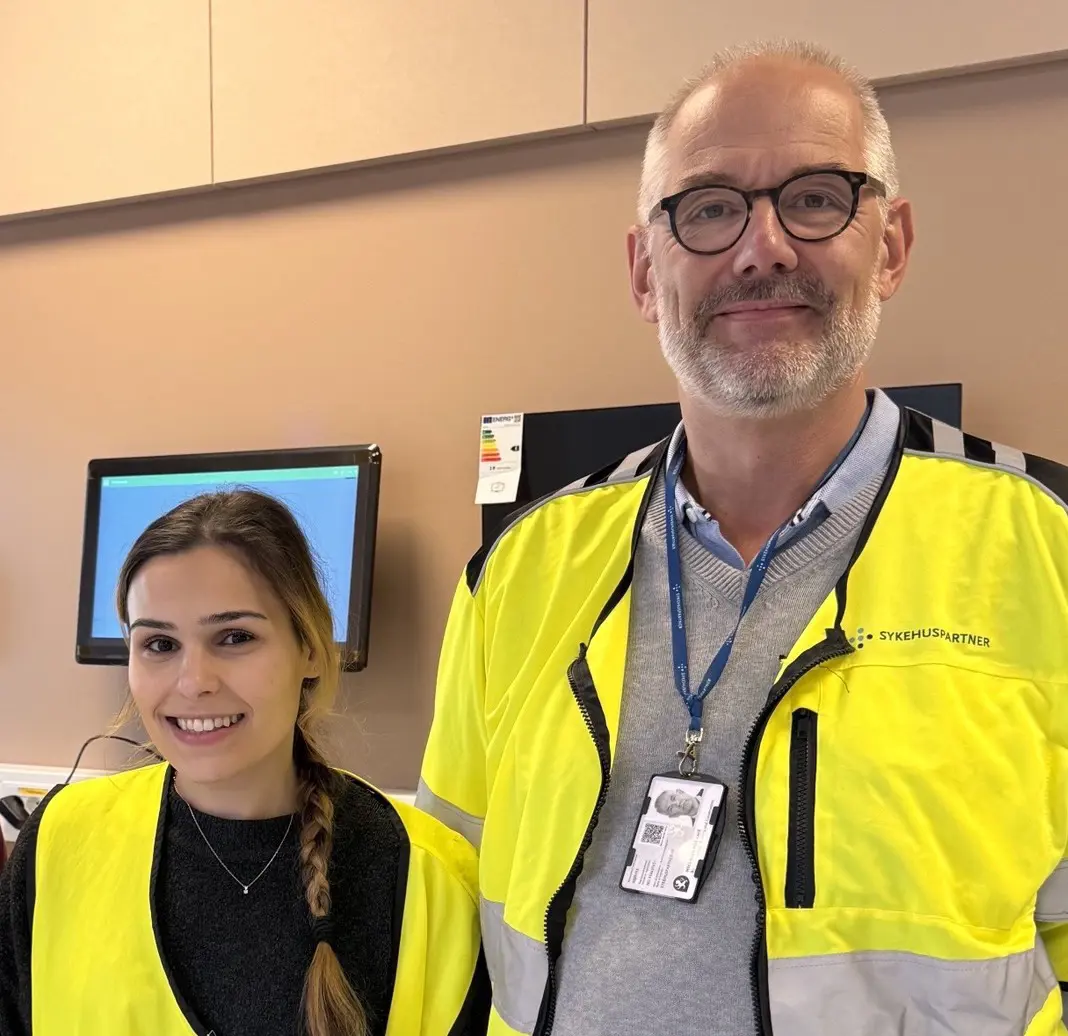 Smilende mann og kvinne i gule vester som poserer for et bilde