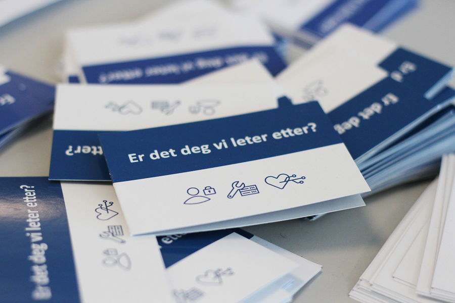 Mange brosjyrer på et bord, med teksten "er det deg vi leter etter"?format=webp&. Foto.