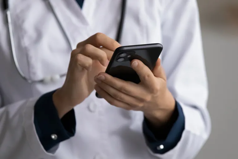 Lege som trykker på en mobiltelefon