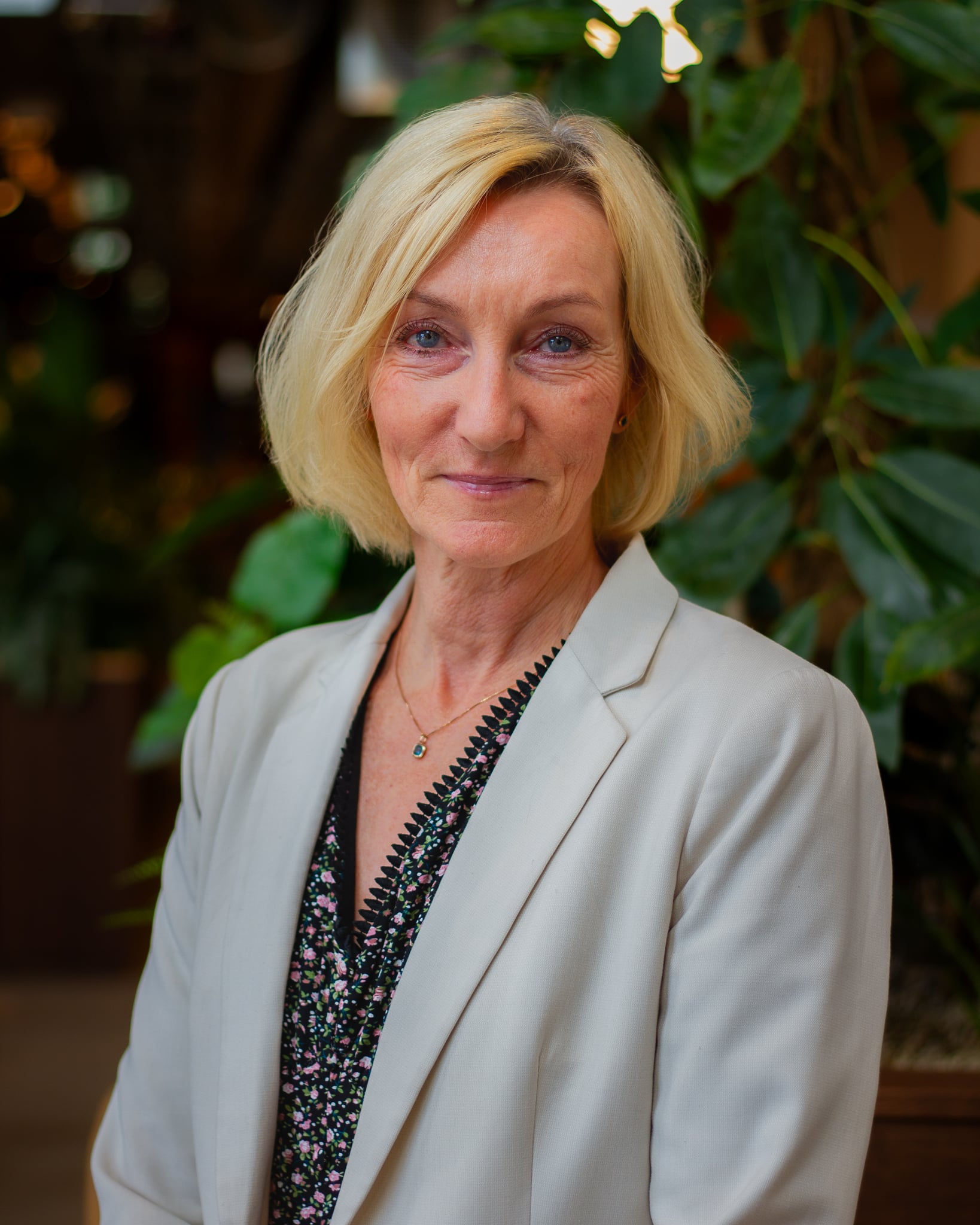 Blond woman in a suit, smiling, looking at the camera. Photo.