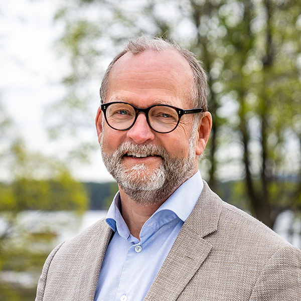 Smilende mann med skjegg og briller. Foto.