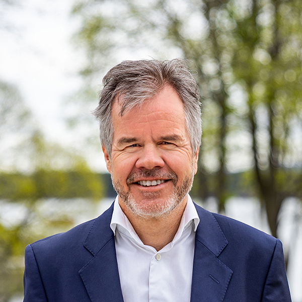 En mann med grått hår og skjegg som smiler til kameraet. Foto.