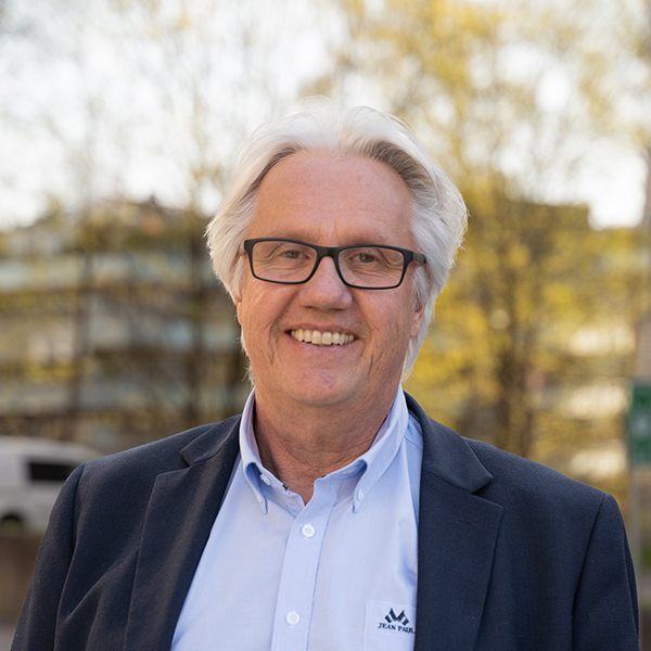 Smilende mann med hvitt hår og briller. Foto.