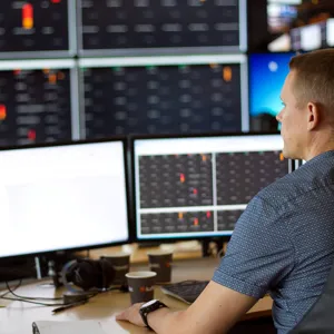 En mann som sitter ved et skrivebord med en datamaskin og en skjerm