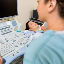 En lege som tar ultralyd på en pasient som ligger på en seng