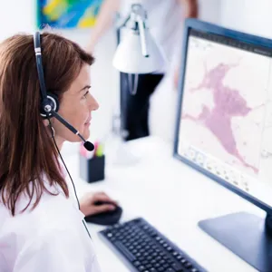 Woman in white coat in front of computer screen