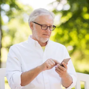 Eldre mann i park med smarttelefon