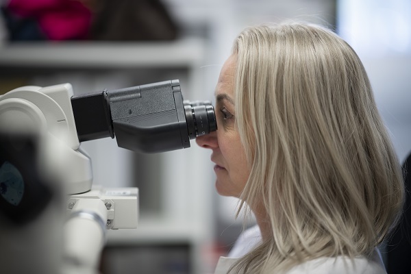 Bilde av sykepleier som ser inn i mikroskop eller lupe