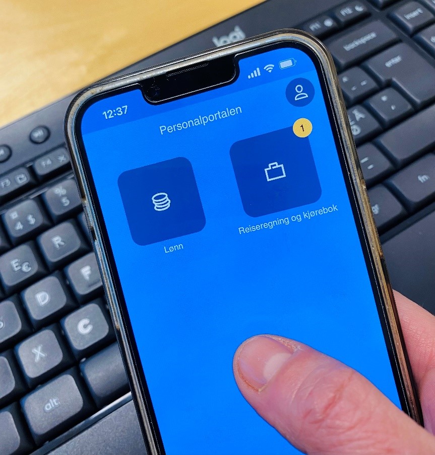 Personalportalen vist på mobilskjerm med tastatur i bakgrunnen. Foto.