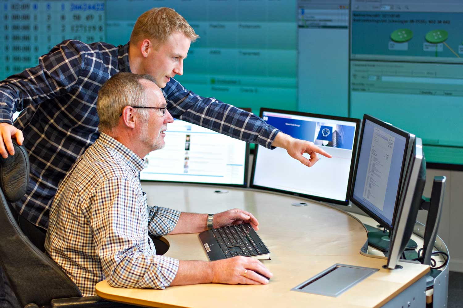 To menn som ser på en dataskjerm. Foto.