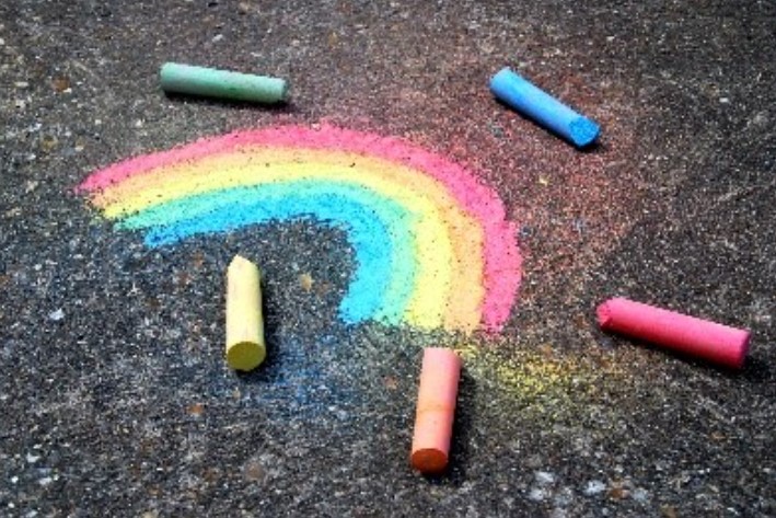 Regnbue tegnet på asfalt med fargekritt. Foto.