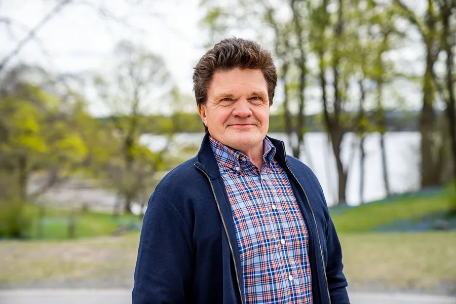 Smilende mann med mørkt hår. Foto.