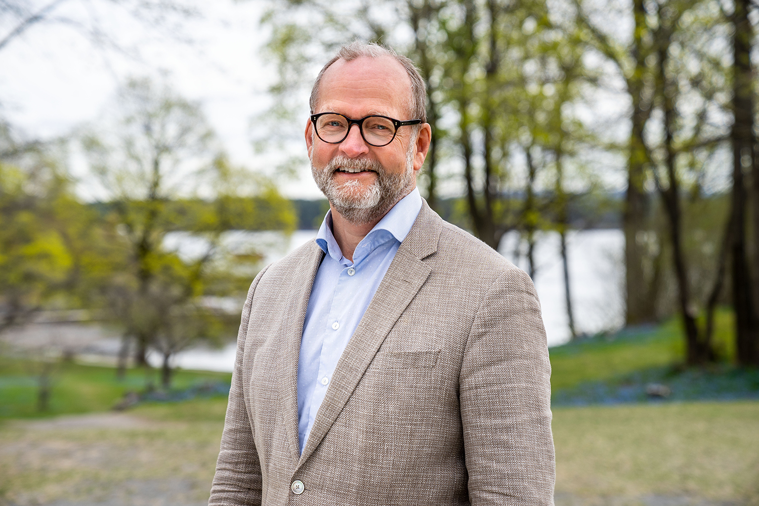 Smilende mann med briller og skjegg. Foto.