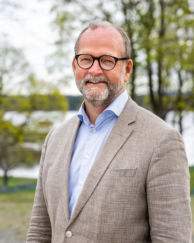 Smilende mann med briller og skjegg. Foto.