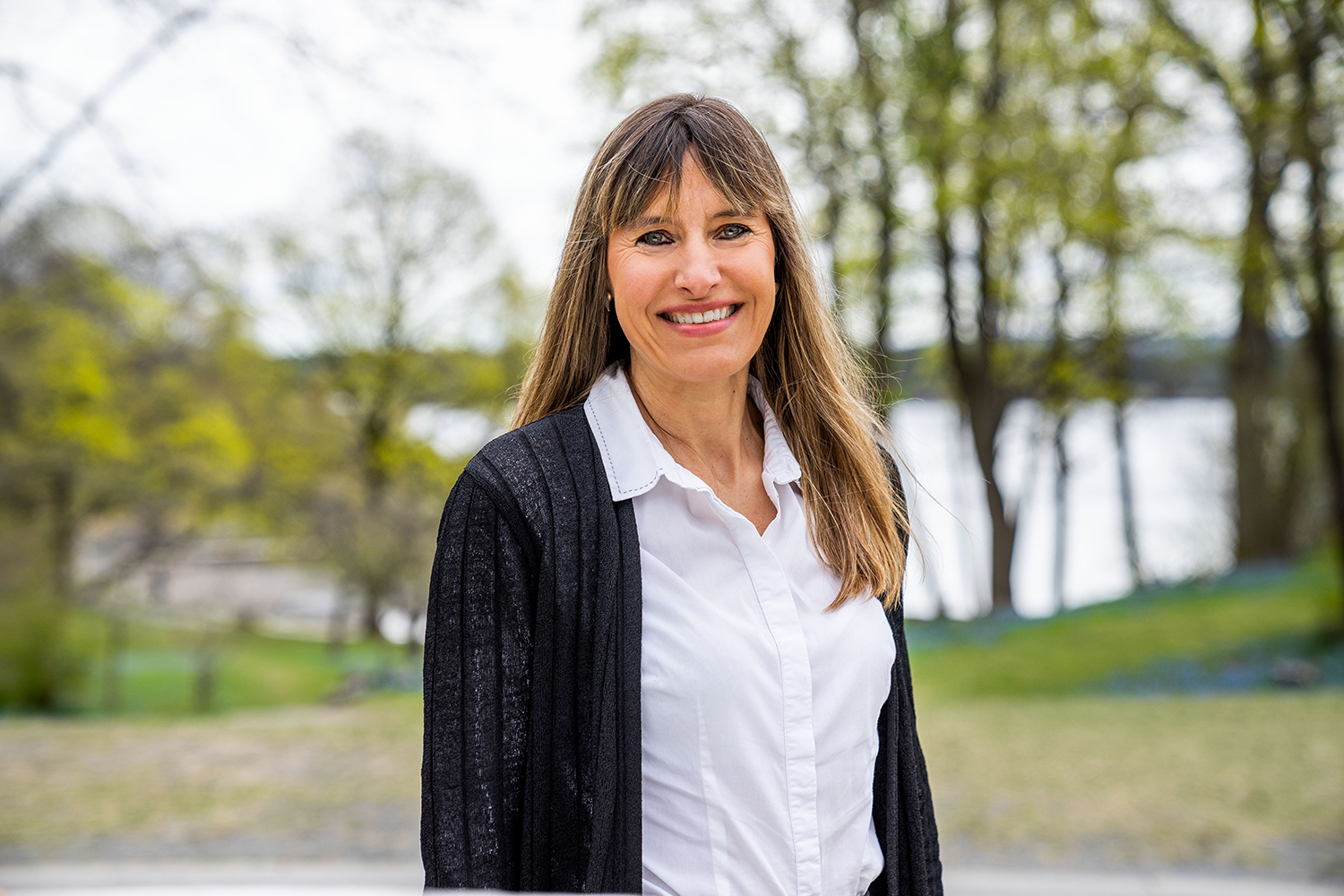 Smilende dame med langt mørkeblondt hår. Foto.