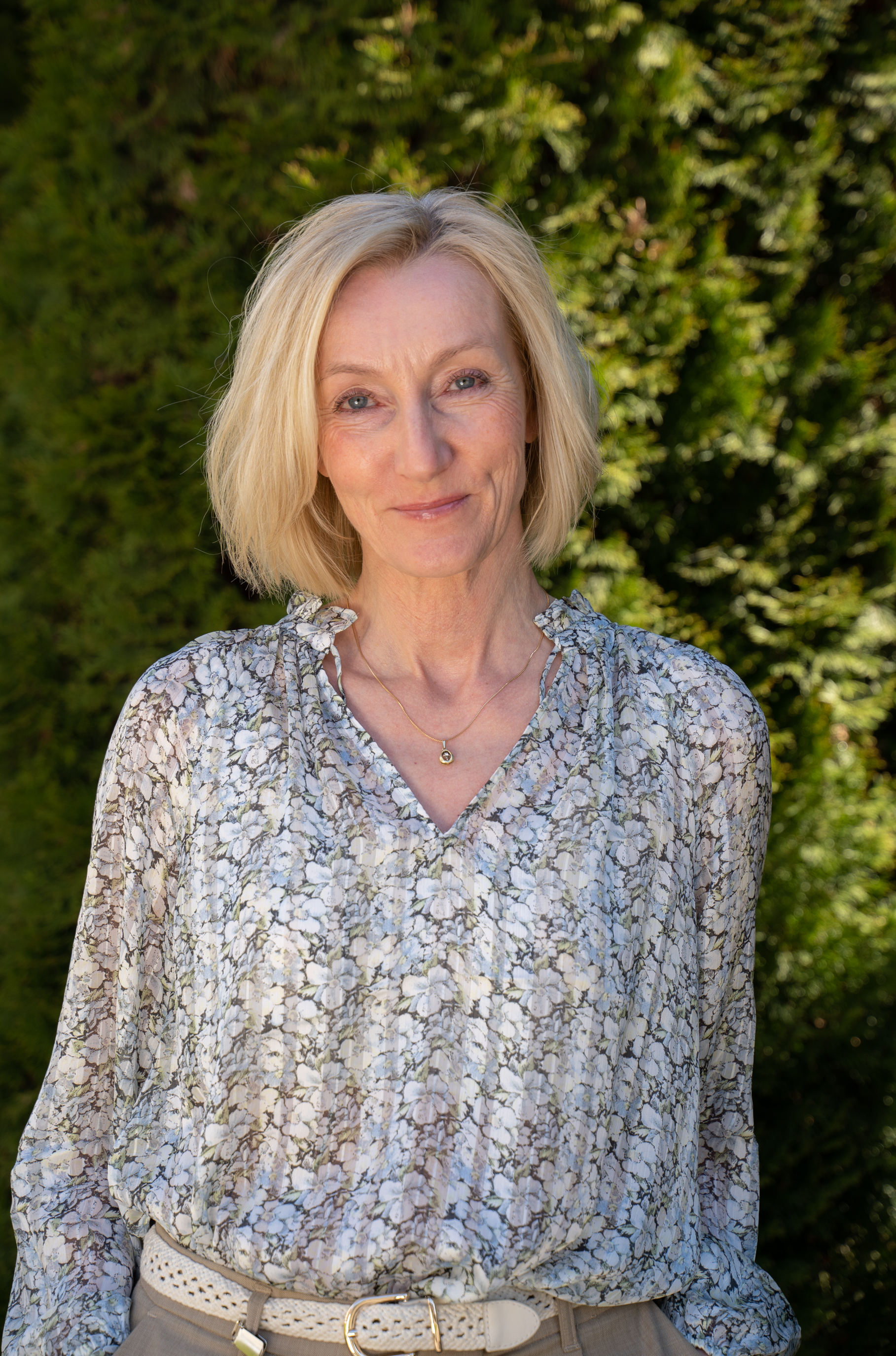 Smilende dame med lyst, halvlangt hår. Foto.