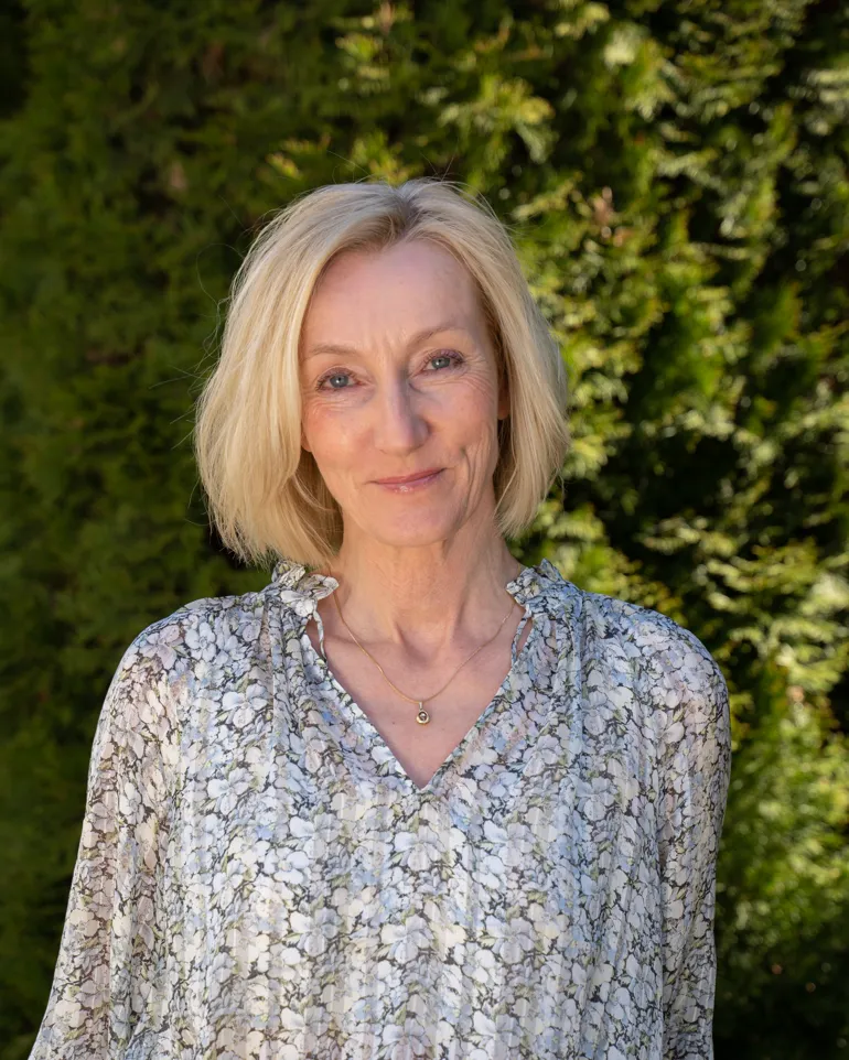 Smilende dame med lyst, halvlangt hår. Foto.