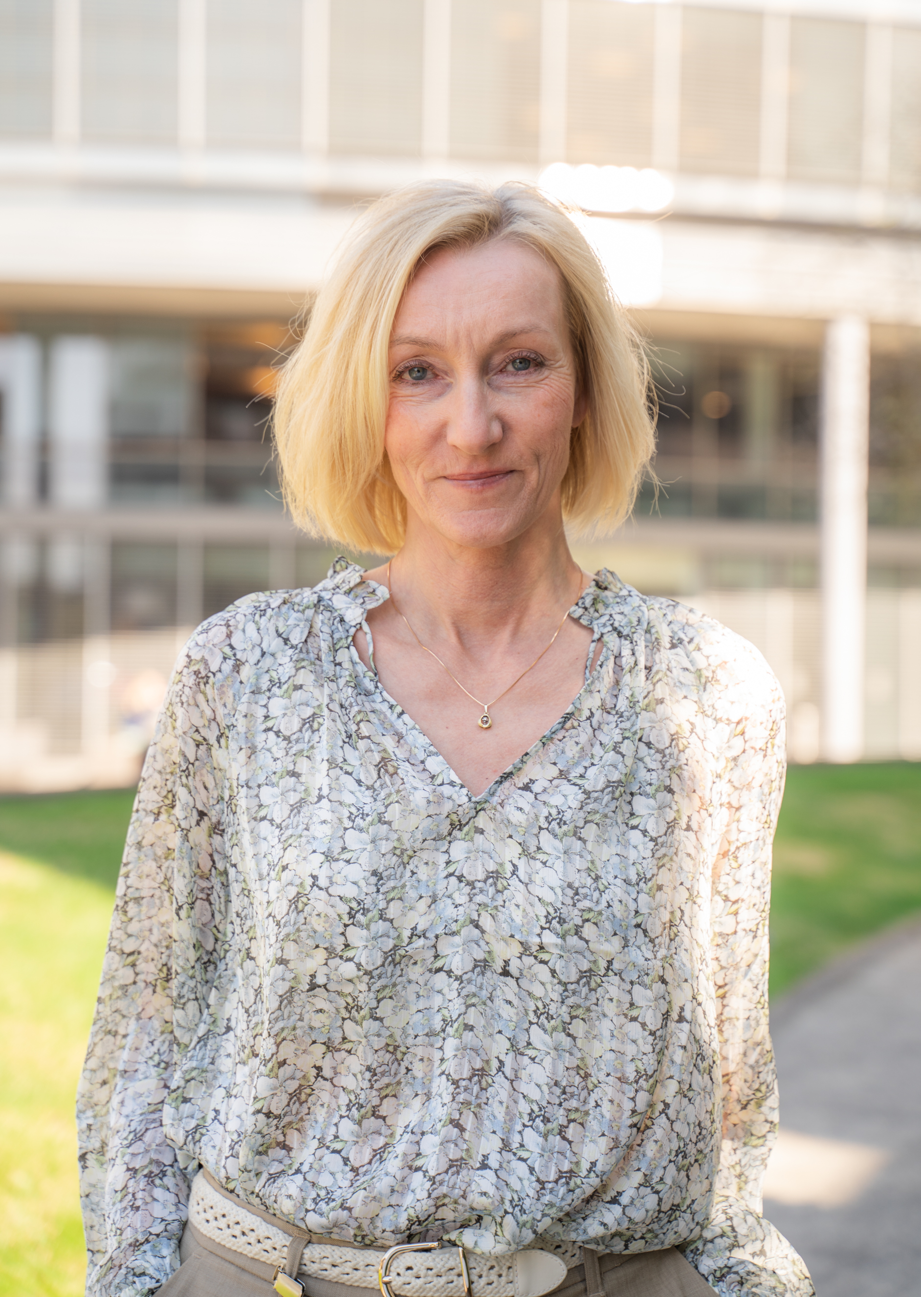 Smilende kvinne med halvlangt, blondt hår. Foto.