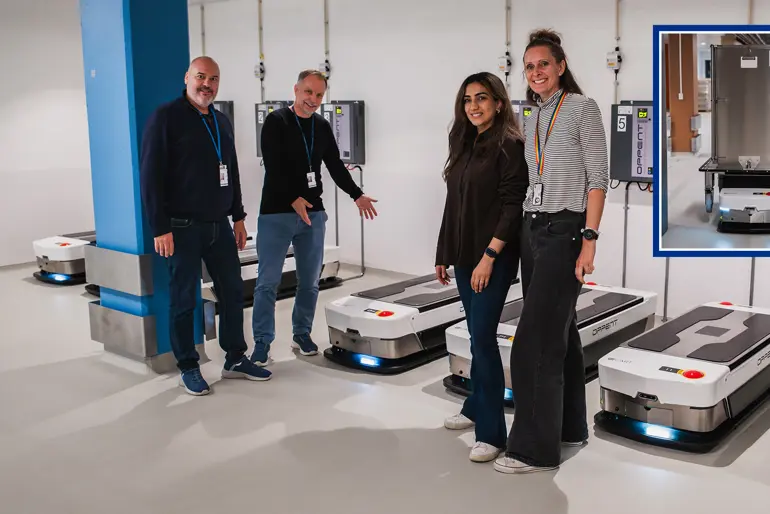 En gruppe mennesker som står ved siden av en robotmaskin. Foto