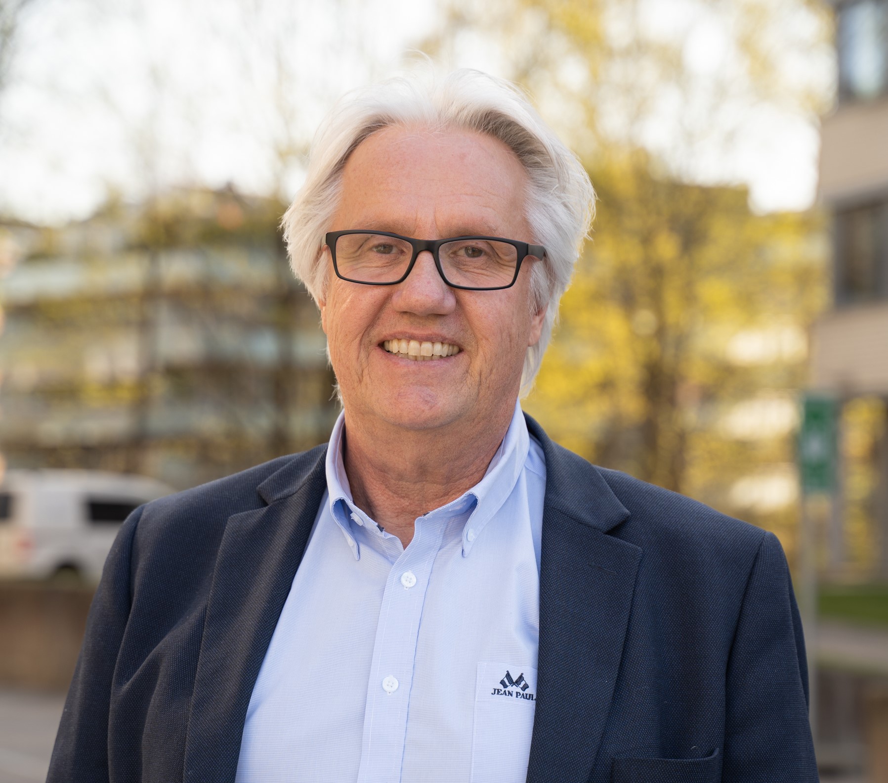 Smilende mann med briller og hvitt hår. Foto.