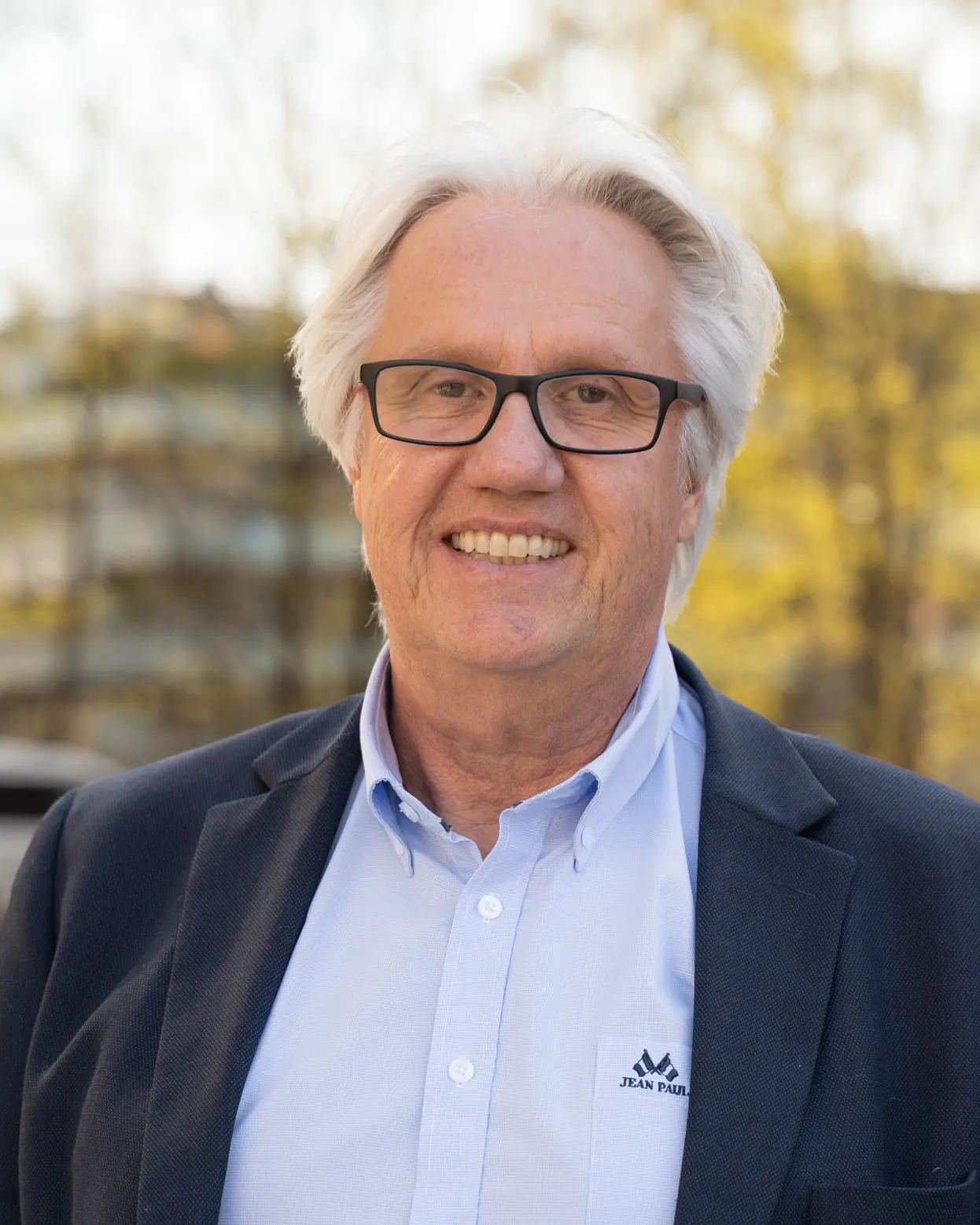 Smilende mann med briller og hvitt hår. Foto.