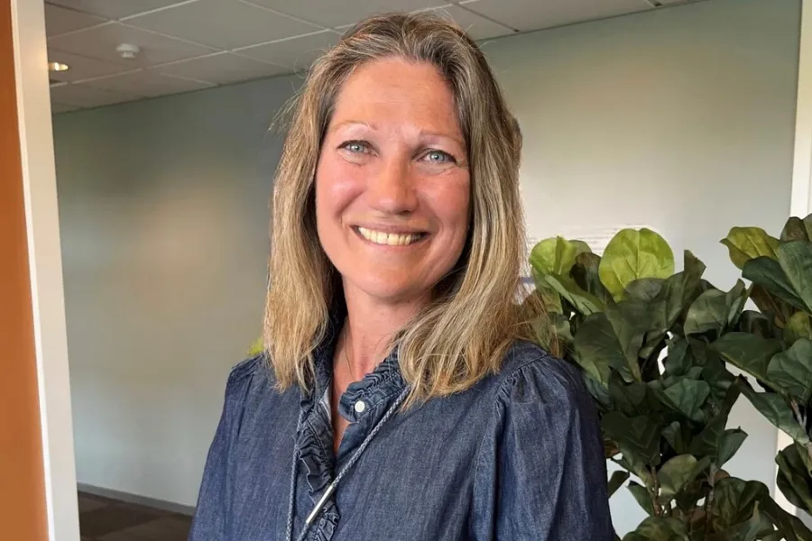 Smilende kvinne med mellomlangt, blondt hår. Foto.