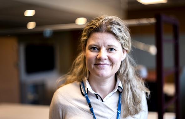 Smilende kvinne med langt, blondt hår. Foto.