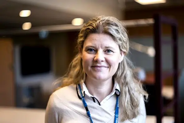 Smilende kvinne med langt, blondt hår. Foto.