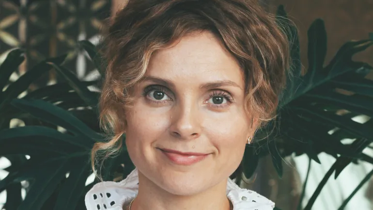 Smilende kvinne med krøllete hår. Foto.