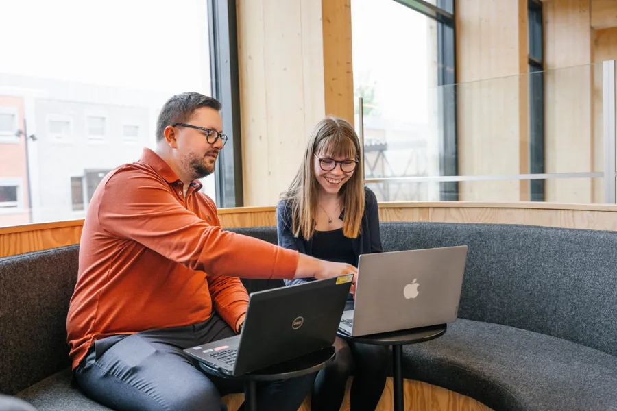 En mann og en kvinne som sitter i en sofa og ser på skjermen på en bærbar datamaskin. Foto.