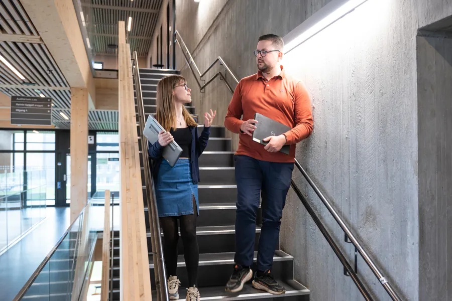 En mann og en kvinne står i en trapp og snakker sammen. Foto.