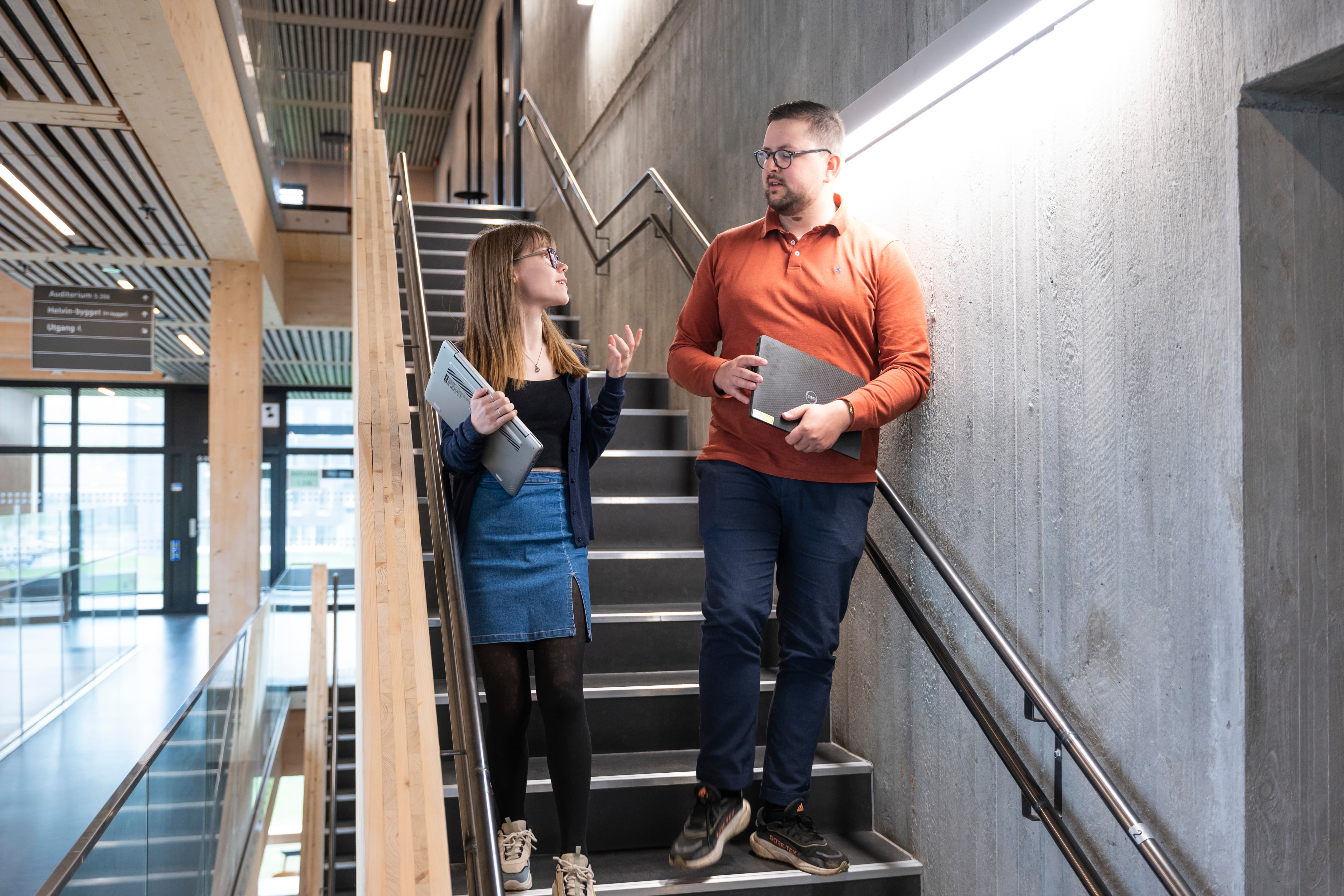 En mann og en kvinne står i en trapp og snakker sammen. Foto.