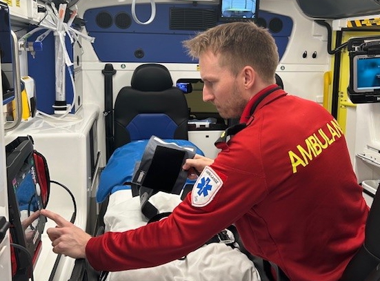 Ambulansemedarbeider betjener instrument i ambulanse. Foto.