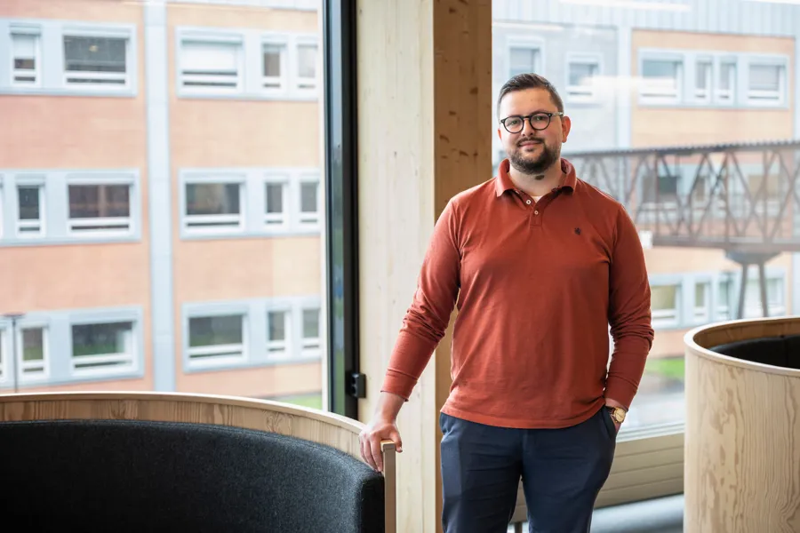 En mann som står ved et vindu i et kontorlokale. Foto.