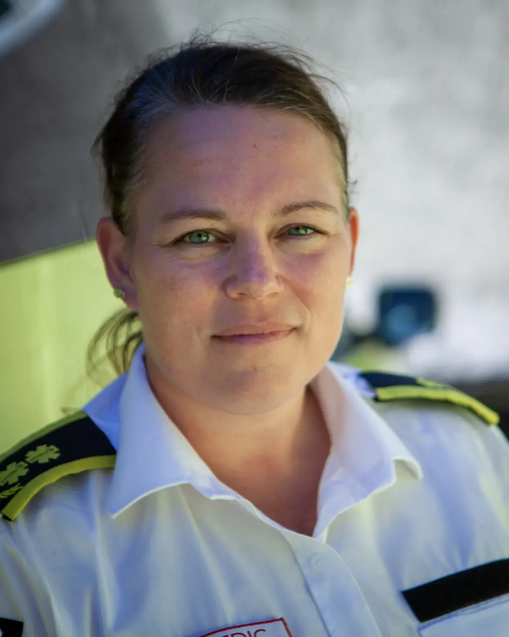 Kvinne i hvit skjorte med ambulansemerker. Foto.
