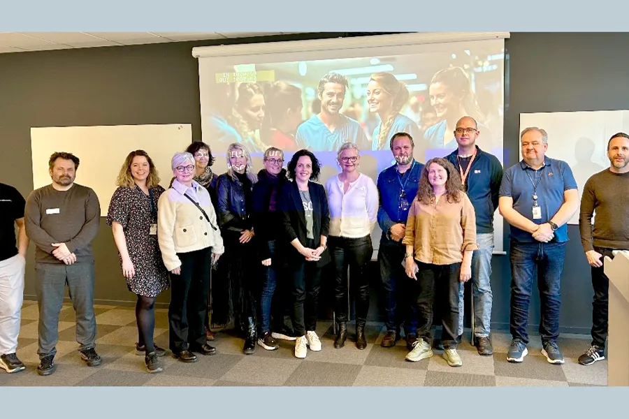 En gruppe mennesker i et møterom som poserer for et bilde. Foto.