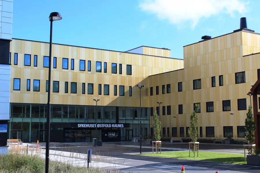 Gul blokk/kontorbygg i flere etasjer. Det står "Sykehuset Østfold Kalnes" over inngangen.