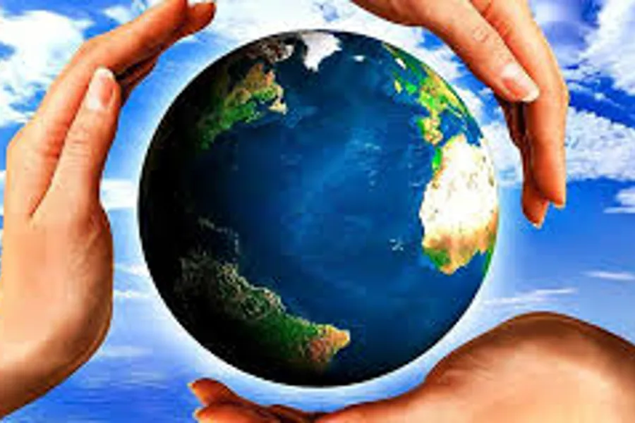 Hender som holder om en jordklode. Blå himmel og skyer i bakgrunn. Foto.