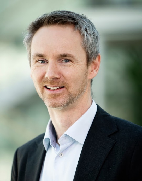 Smilende mann i dress. Foto.