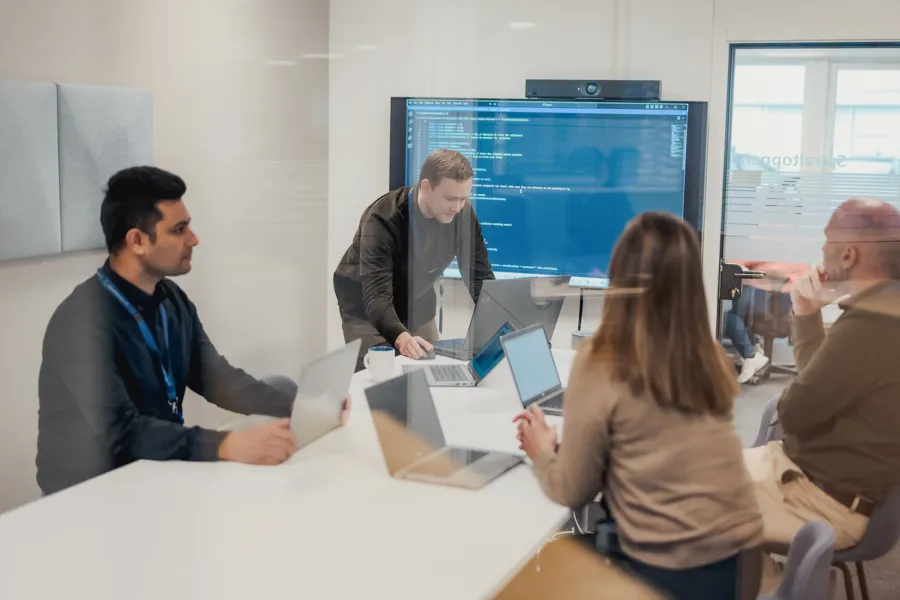 En gruppe mennesker som sitter rundt et bord med bærbare datamaskiner. Foto.