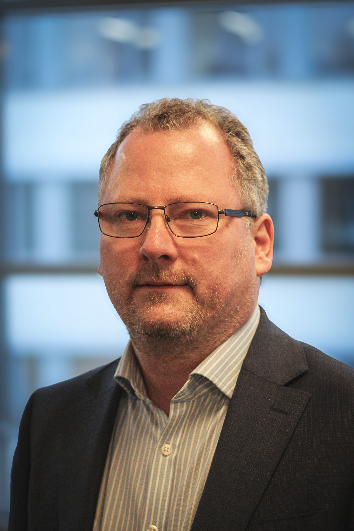 Mann med grått hår og briller. Foto.