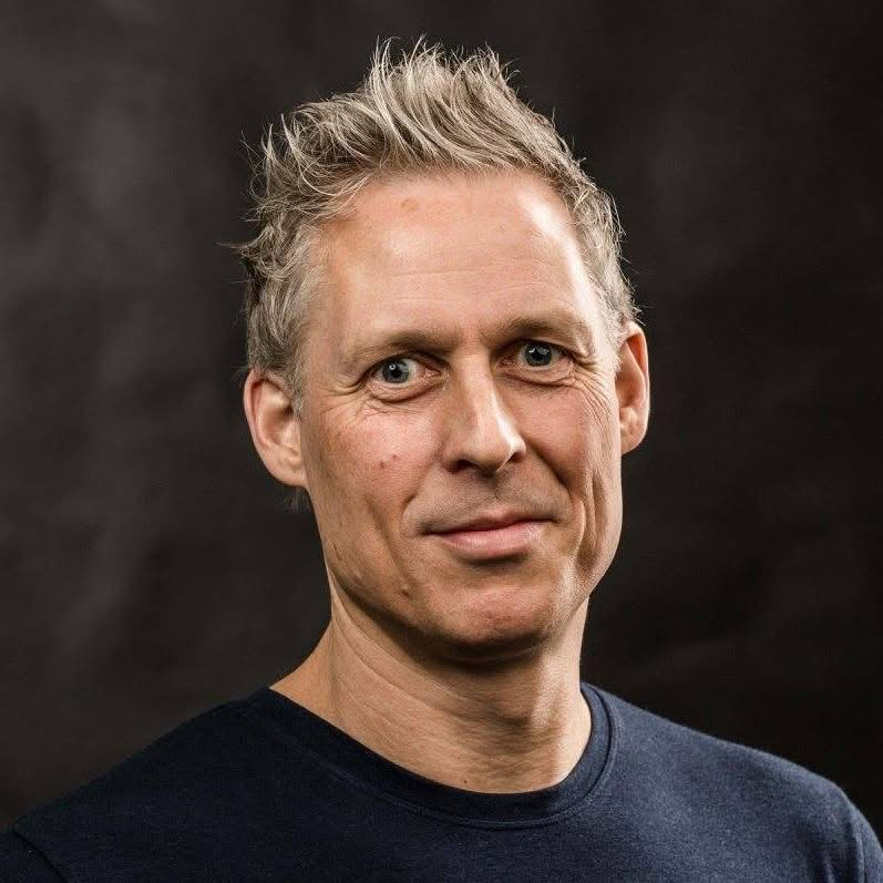 Smilende mann med kort, grått hår. Foto.